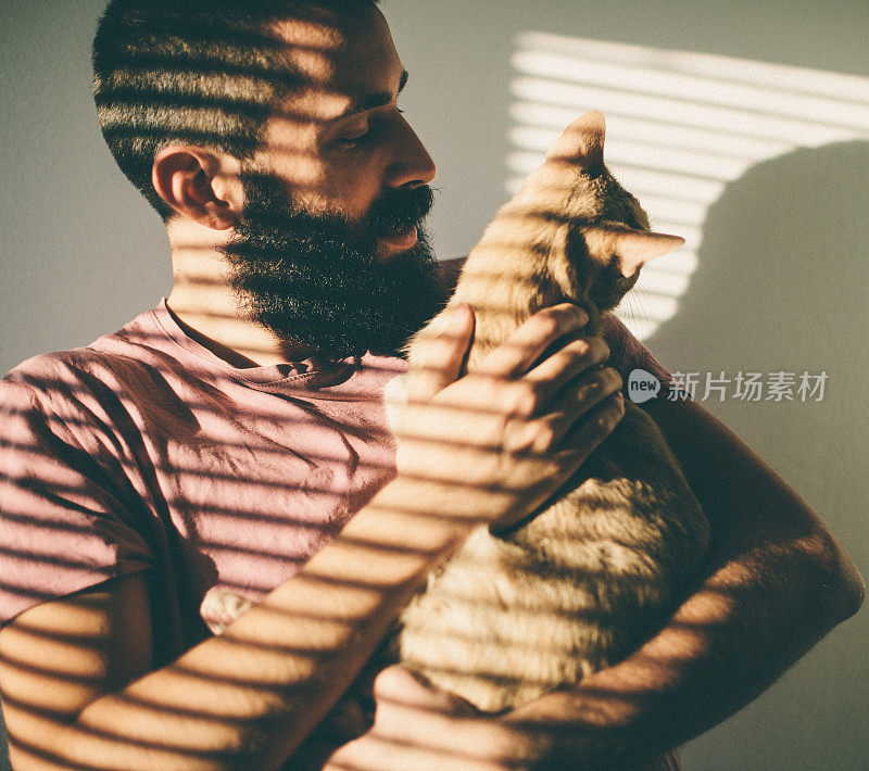 长胡子的年轻人拥抱着他美丽的猫