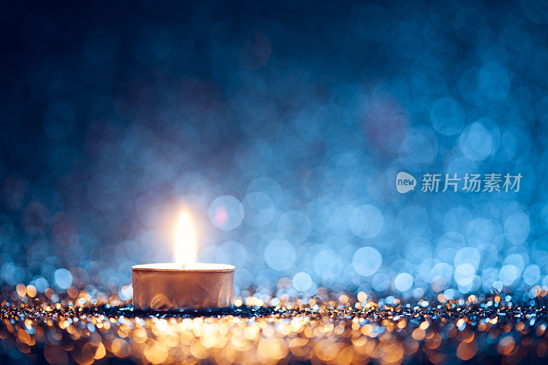 点燃蜡烛散焦蓝色背景-圣诞茶灯