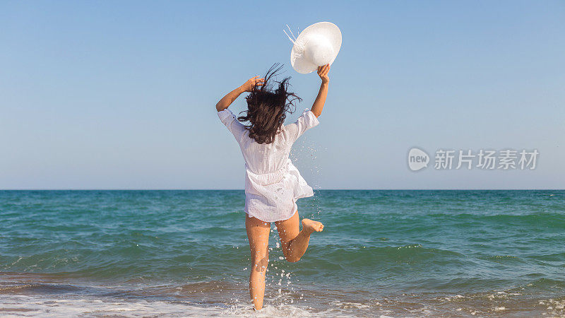穿白裙子的女人在沙滩上跳。