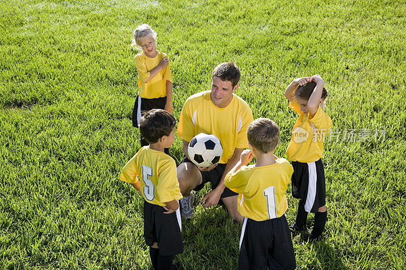 教练带领一群孩子踢足球