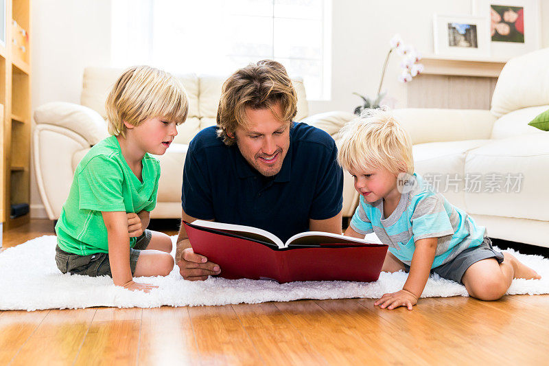 父亲正在给他的两个小男孩读书。