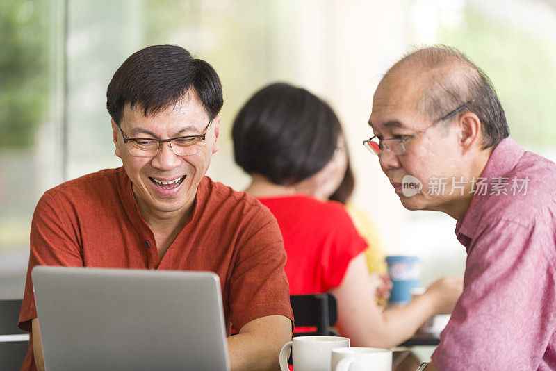 两个成熟的男人在户外咖啡馆用笔记本