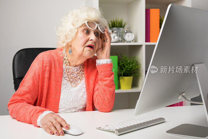 奶奶一边在办公室工作，一边难以置信地看着电脑