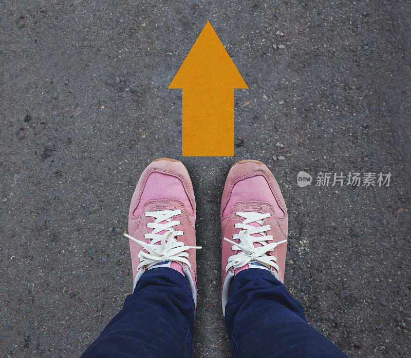 一双鞋站在黄色箭头的路上。