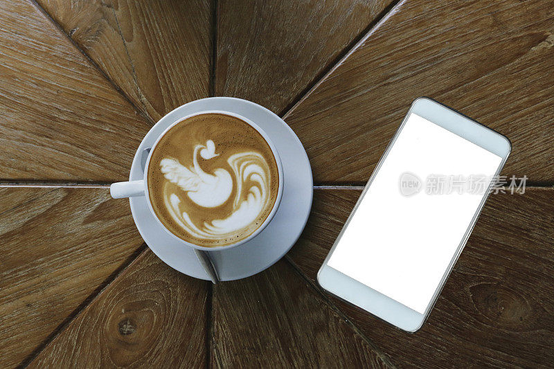 顶视图的咖啡拿铁艺术风格在白色陶瓷杯除了白色智能手机