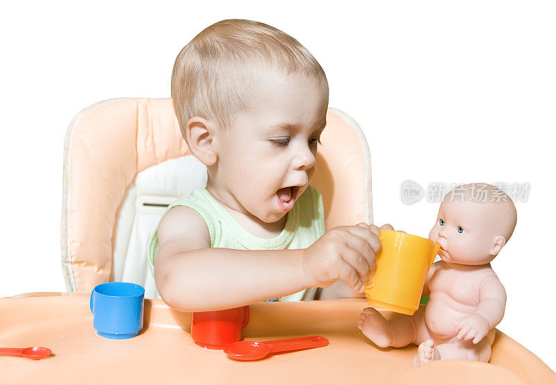 婴儿玩娃娃，孩子喂玩具，孩子坐在桌子前，白色孤立