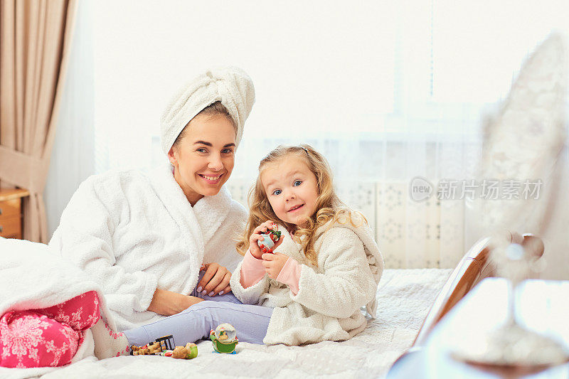 母亲和女儿穿着浴衣和毛巾在ro的床上