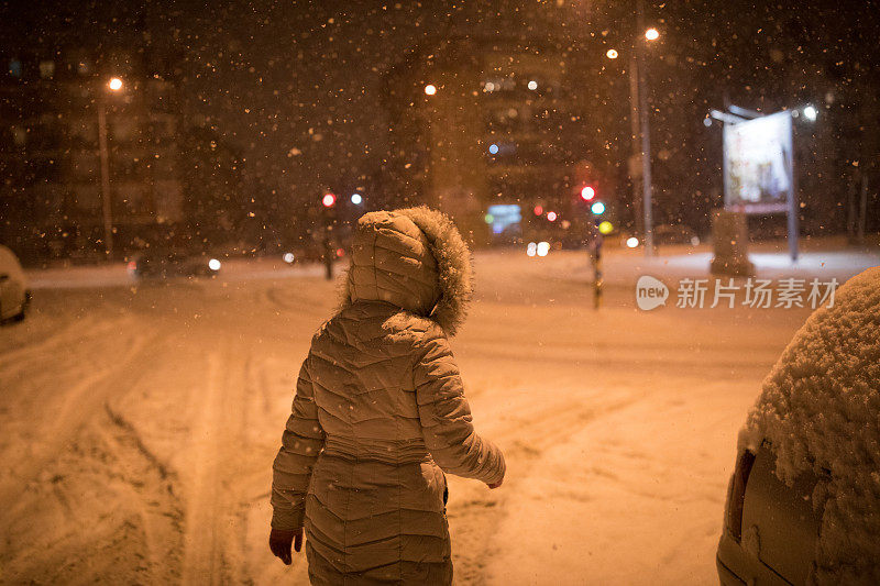 一个女人在下雪的晚上散步