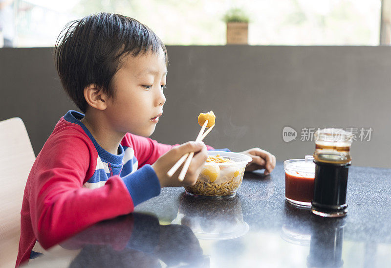 亚洲小孩用筷子吃美味的面条