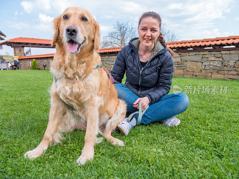 女孩和她的金毛猎犬在户外看着摄像机