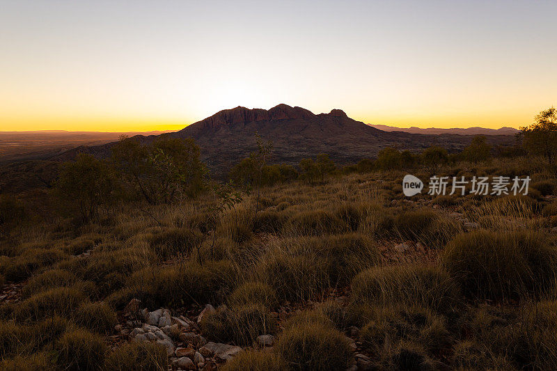 在令人惊叹的澳大利亚沙漠日落的最后一缕阳光中，这座山闪耀着光芒