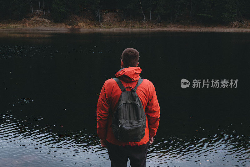 一个背着双肩包的男人，在山湖上游逛