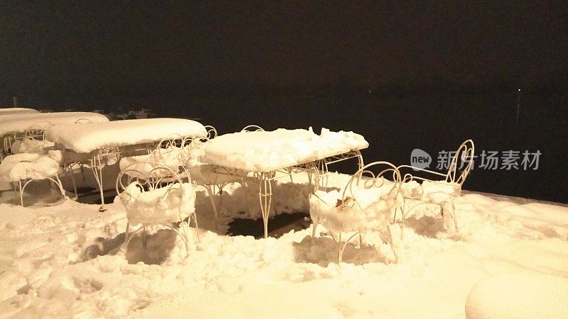 桌子和椅子在晚上覆盖着雪