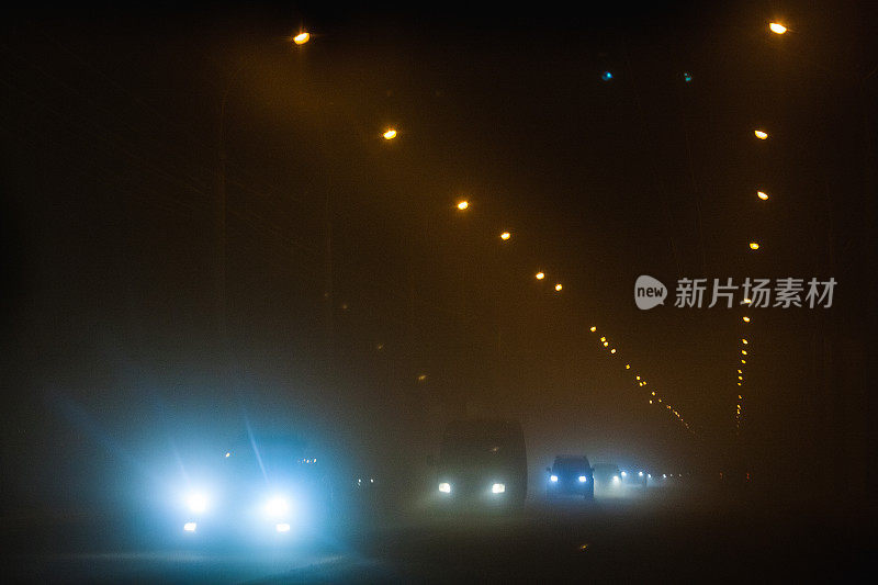 在一个雾蒙蒙的夜晚，高速公路上的汽车和路边的灯柱