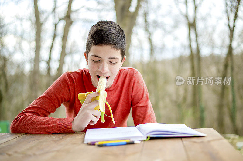 一个在城市公园里学习的少年。吃健康零食的时间到了