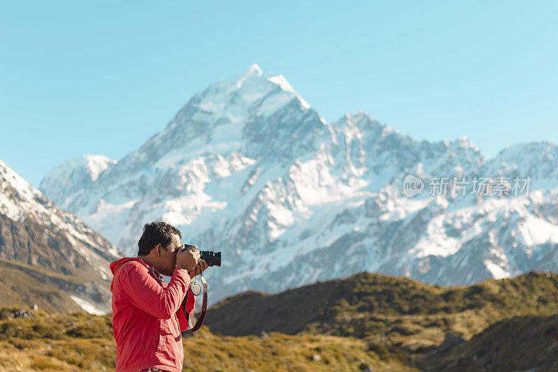 新西兰库克山;一个徒步旅行者在库克山的一条徒步小径上的阳光下拍照。