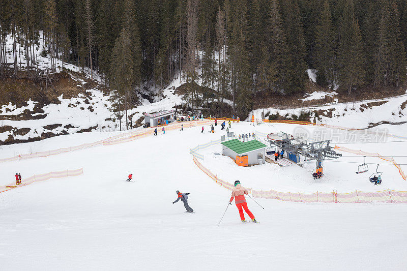 滑雪者和滑雪板运动员正往下走到滑雪缆车上。