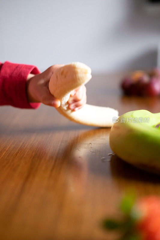 婴儿的手在木桌上摆弄着不同的水果