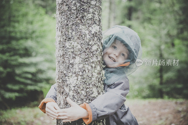 红发小男孩抱着树，戴着蚊帐