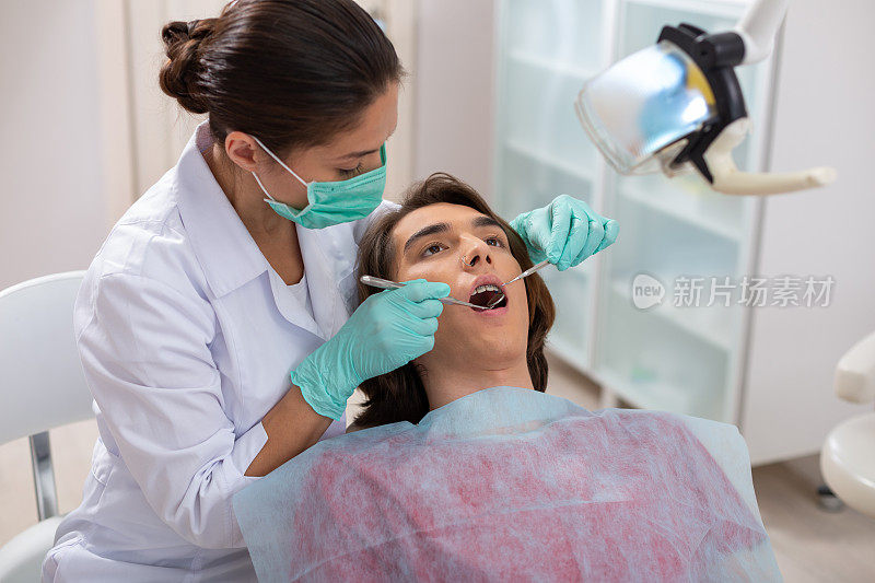 专注的女牙医俯身看着她的男病人