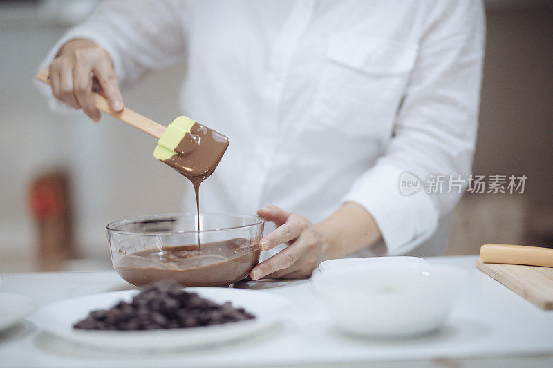 一位亚洲华裔女甜品厨师正在准备巧克力松露，在家里搅拌和切碎巧克力