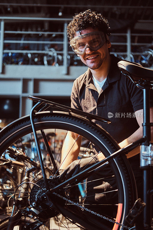戴着防护眼镜的沉思的勤奋的师傅正在车间修理自行车
