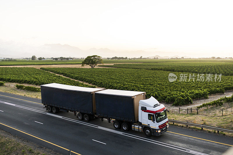 卡车在日出时行驶在高速公路上，穿过碧绿的南非风景