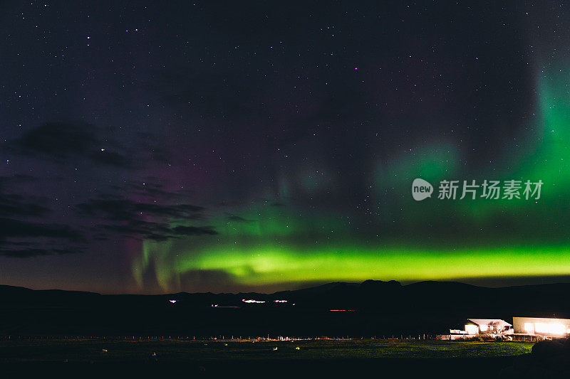冰岛小镇和山区上空的北极光风景