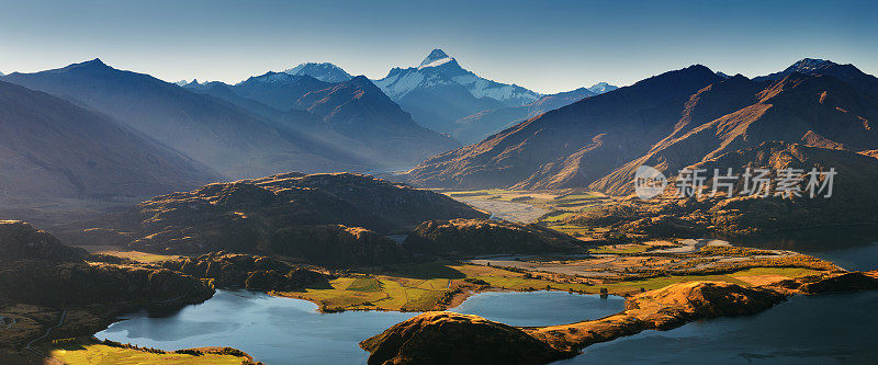 全景在日落的罗伊斯峰之间的瓦纳卡和皇后镇与湖和山的抱负和厨师的新西兰阿尔卑斯山的背景。夏季