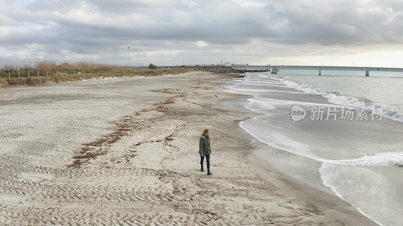 一个孤独的女人在海边漫步
