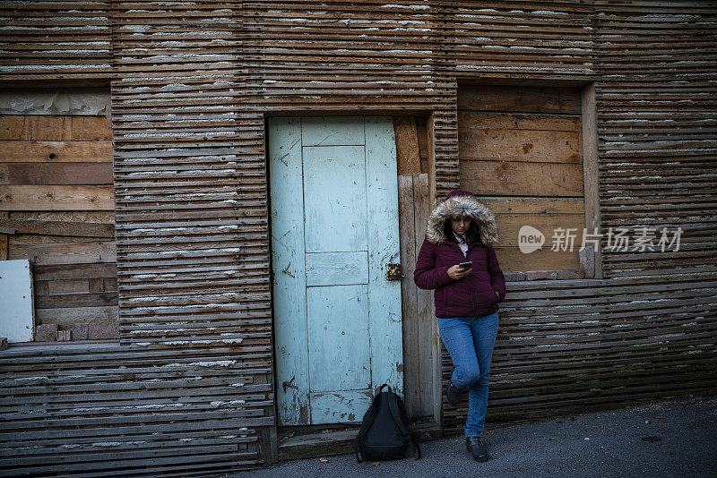 穿着帽衫的年轻女孩在土耳其埃斯基希尔伍德市场街道上五颜六色的木门前等待