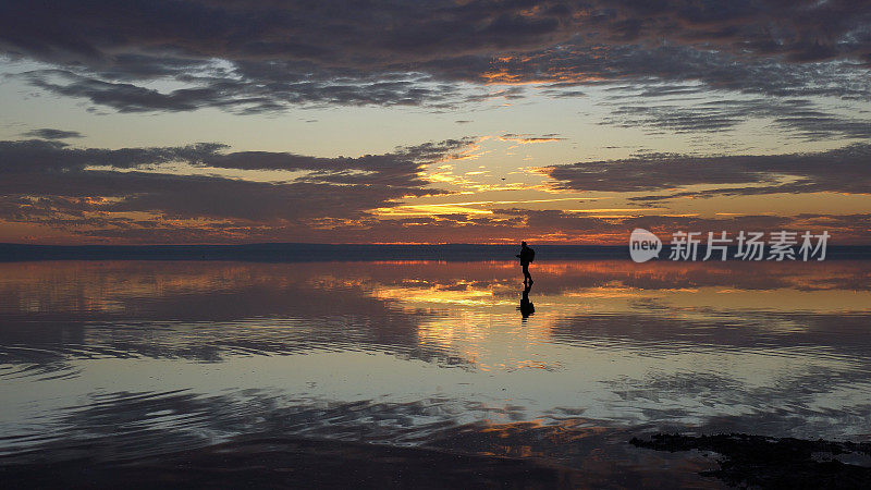 年轻的旅行者在日落时分漫步在盐湖上