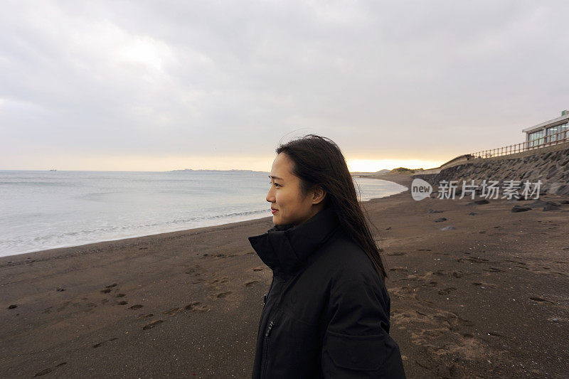 微笑的年轻女子看海滩在日落