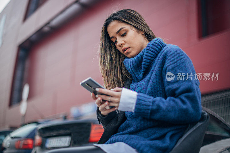 一个女人在停车场用智能手机