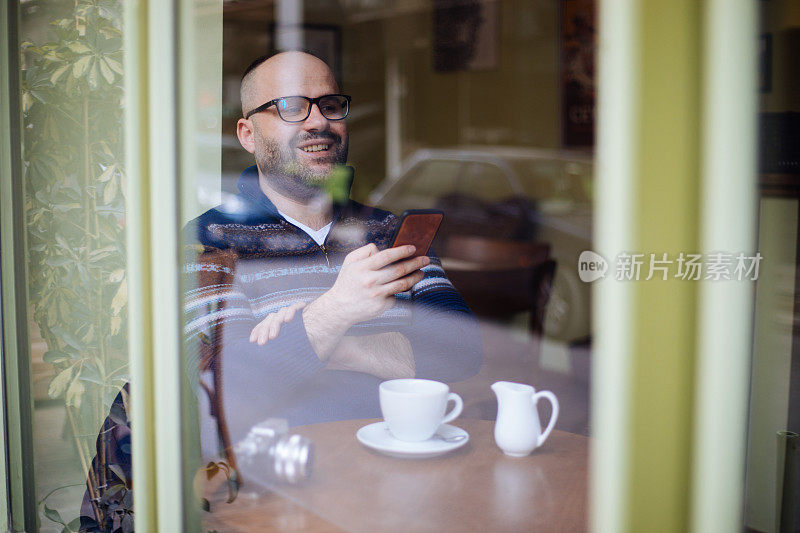 一名男子在咖啡馆使用智能手机