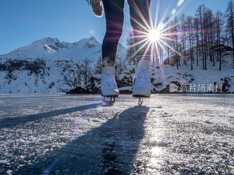 日落时分，在结冰的湖面上穿着溜冰鞋的双脚