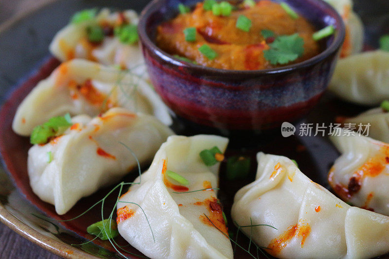 这是蒸过的馍馍(南亚饺子)，用白面粉和水面团填满鸡肉和什锦蔬菜，淋上辣椒油，放在盘子里，周围是用橙子辣酱做的小模子