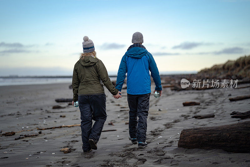 年轻夫妇手持水晶球穿过海滩