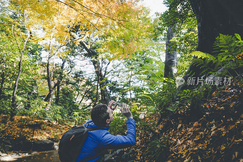 一名男子在登山时用智能手机拍照