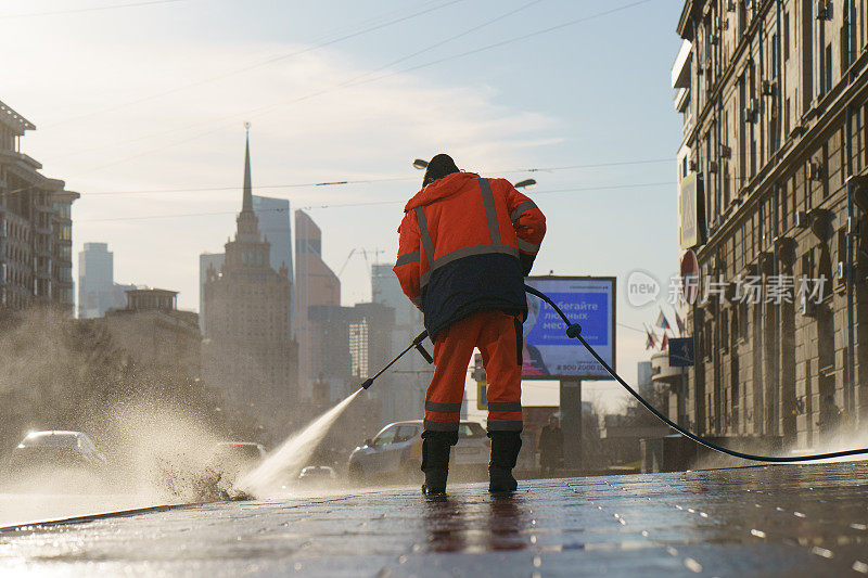 工人从水管浇灌街道。