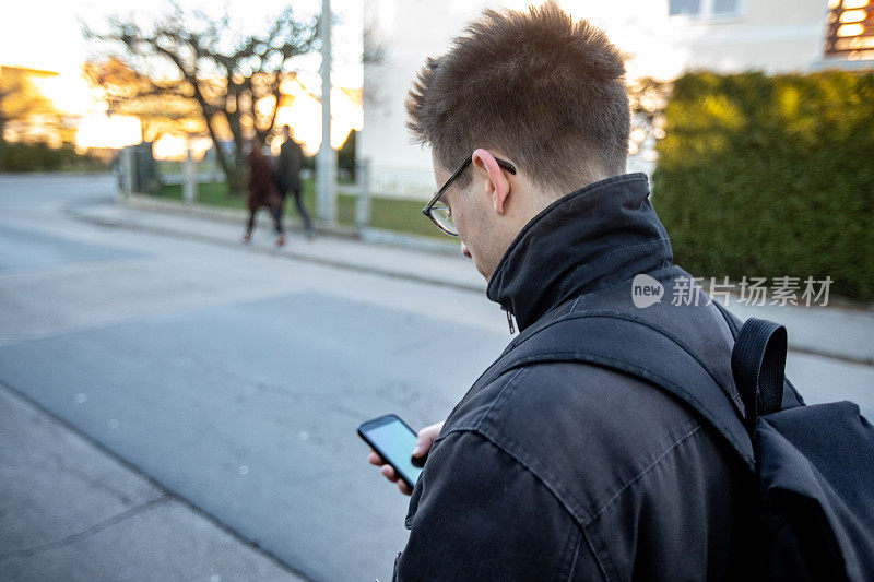 年轻的成年男子在城市街道上使用手机