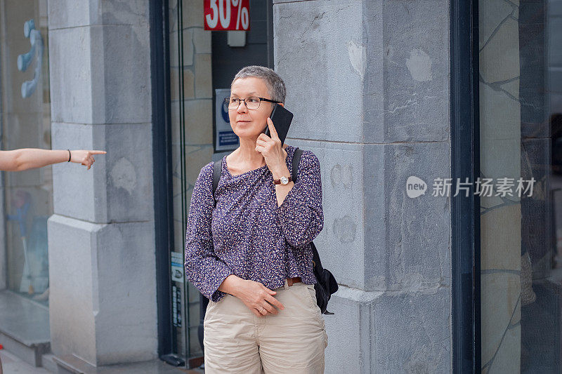 成熟的女人在街上用手机说话