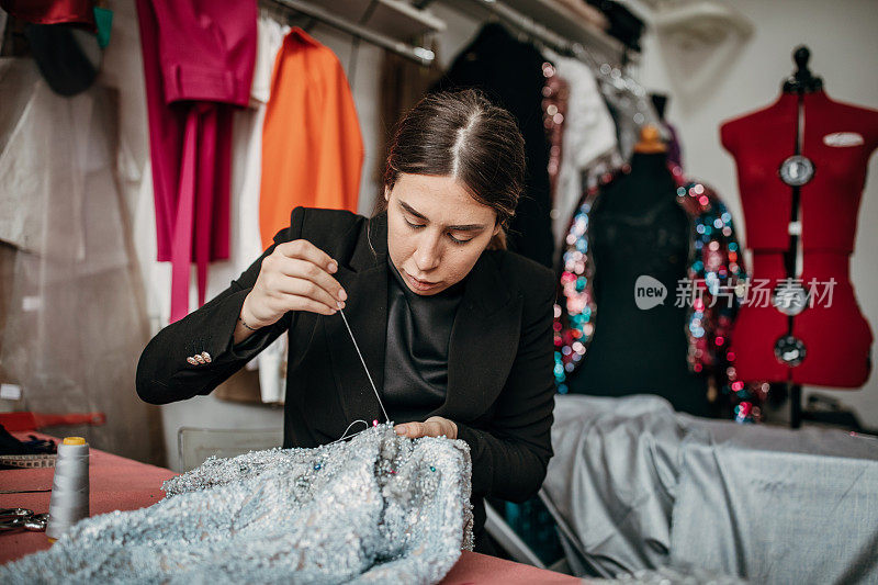 一位女时装设计师正在用针缝纫