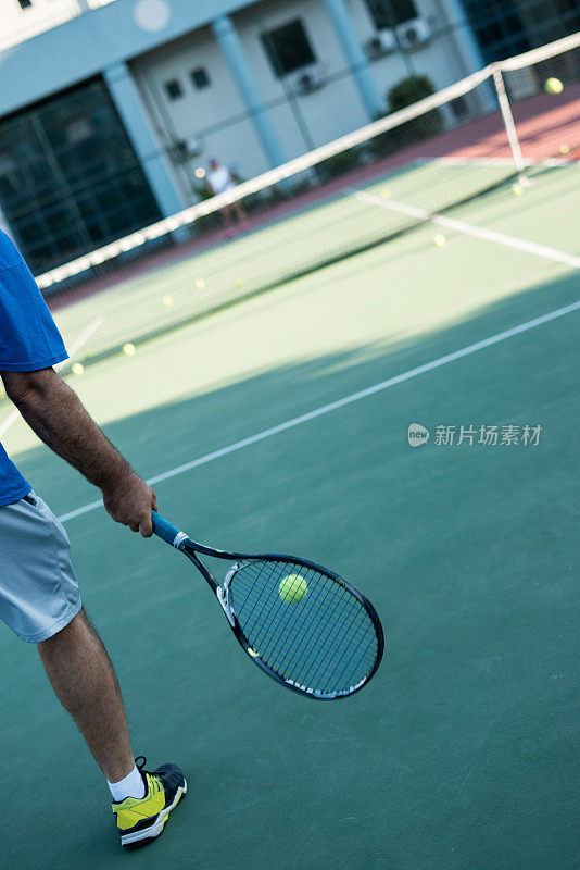 一个网球沙发正在硬地上教网球