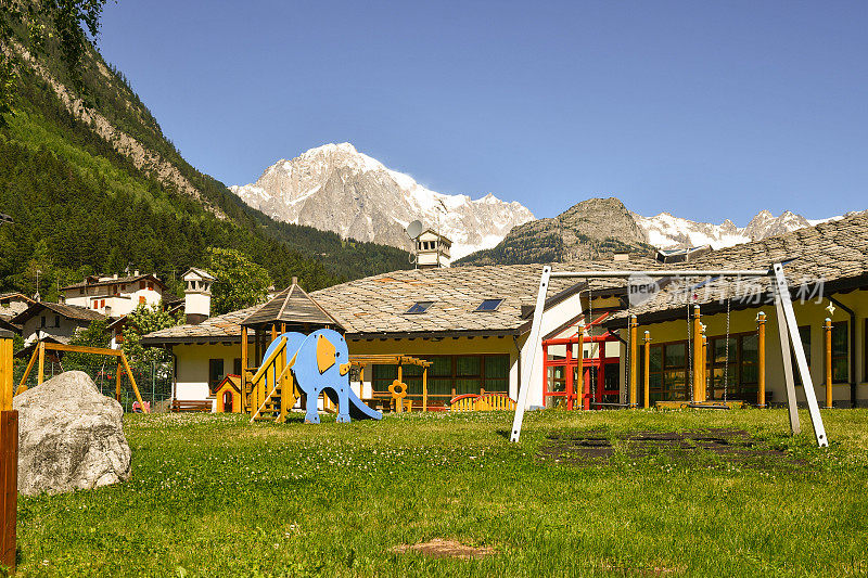 这是意大利奥斯塔的一个幼儿园花园里的孩子们的游乐场，位于阿尔卑斯山古老的村庄，背景是勃朗峰。Pré-Saint-Didier，意大利奥斯塔