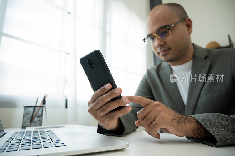 在家工作时使用智能手机和笔记本电脑拉近男性的手的社交距离概念。手指在手机上发短信。