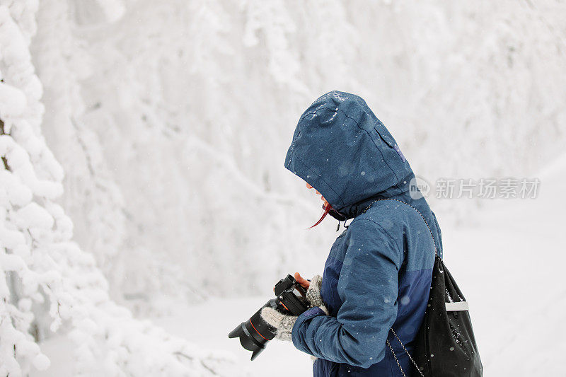 女摄影师在雪天的大自然中拍照