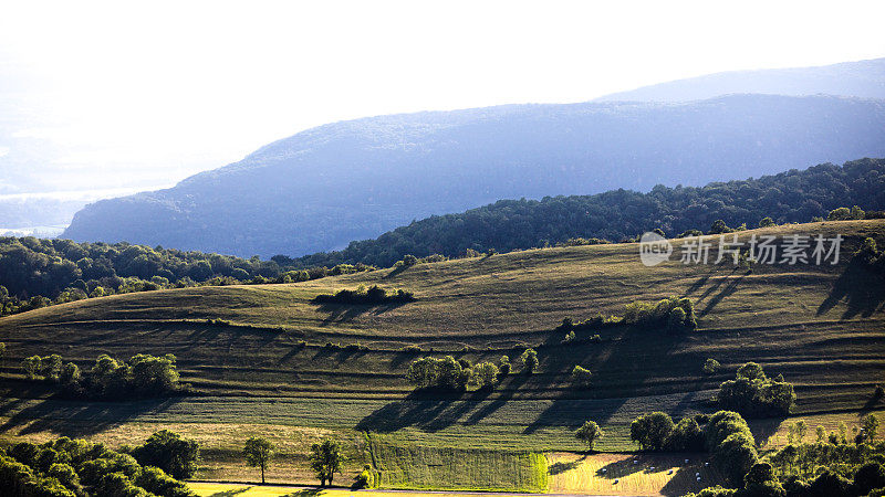 在法国阿尔卑斯山的春天日落时与草地的山顶远处的景色