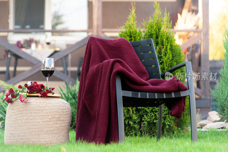 花园里的椅子上有华丽的红毯，还有一杯红酒