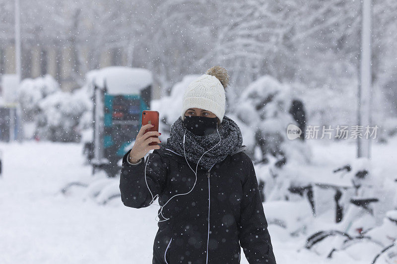 马德里，一个下雪天，女孩用手机拍照。